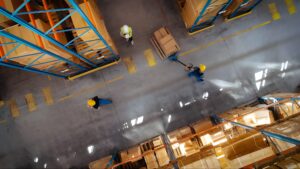 نمایی از انبار با کارگران و جابجایی بسته‌ها، مرتبط با مدل‌سازی شایستگی در مدیریت عملیات